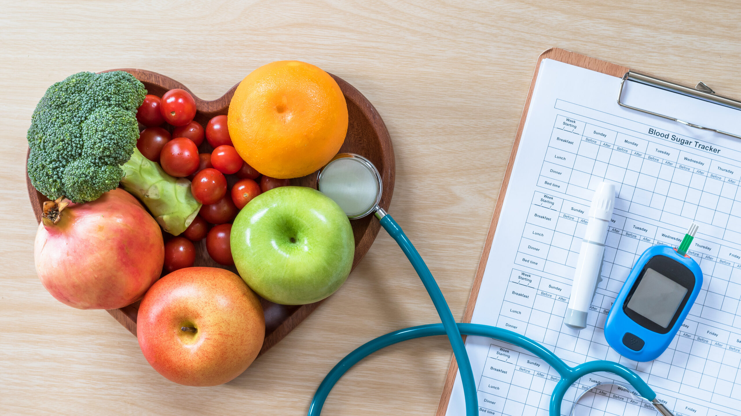 Fruits and Vegetables in a heart-shaped holder. Doctor equipment to the right on top of clipboard with pen.